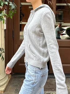 Vue latérale du cardigan en tricot gris avec capuche, fermeture éclair et bords-côtes