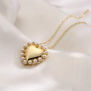 Detailed close-up of a heart pendant with small white pearls on soft white silk fabric