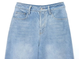 Détails du pantalon en jean bleu clair avec bouton en métal et coutures des poches
