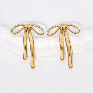 Boucles d'oreilles nœud en acier inoxydable plaqué or 18k sur fond texturé blanc