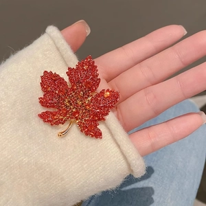 Elegant red maple leaf brooch in gold alloy held in hand for size visualization