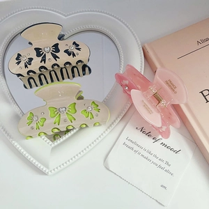 Three acetate butterfly claw clips with rhinestones and ribbon designs on a vanity table