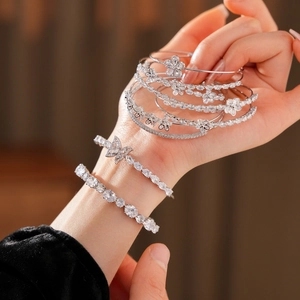 Détail du bracelet fleur en zircon argenté et des bracelets papillon sur le poignet