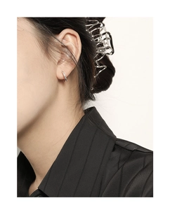 Close-up of a model wearing minimalist silver geometric hoop earrings on a clean background