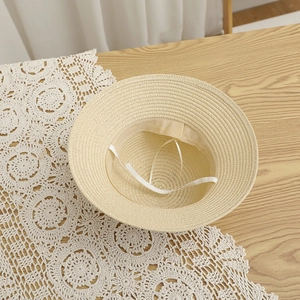 Detail of a straw sun hat featuring a breathable inner band and adjustable white wind rope