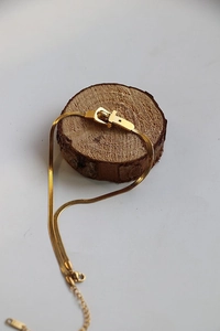 Dettaglio della collana dorata a maglia serpente con fibbia a ferro di cavallo