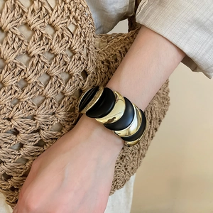 Macro detail of the gold and black moon-shaped modular segments on the elastic bracelet
