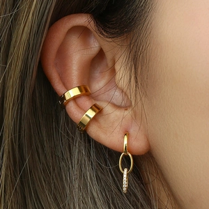 Gros plan sur des boucles d'oreilles pendantes dorées avec zircons et bagues d'oreille