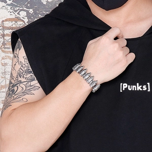 Close-up of punk style silver spike bracelet worn with industrial aesthetic and tattoos