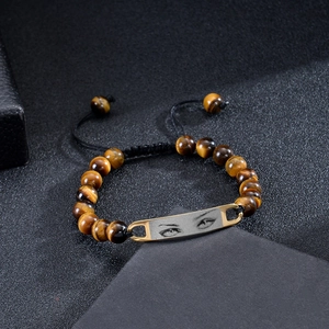 Macro detail of custom stainless steel eye plate on braided tiger eye stone bead bracelet