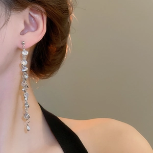 Close-up of elegant long silver tassel earrings with round zircons on a female model