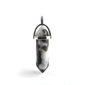 Macro shot of hexagonal black and white stone pendant with silver metal bail attachment