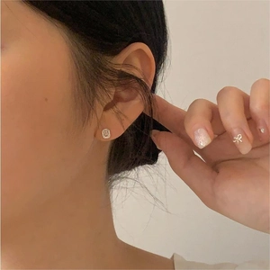 Macro shot of cushion-cut halo zircon stud earrings in 925 sterling silver on woman ear