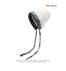 Détail du bonnet d'hiver en peluche blanc cassé avec protège-oreilles bleu gris et longs liens