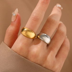 Polished chunky gold and silver curved stainless steel rings worn by a model
