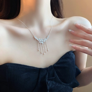 Detail of silver floral fringe necklace with teardrop charms on a black bustier