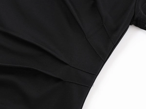 Gros plan des coutures et des plis à la taille sur ce t-shirt noir ajusté et contemporain