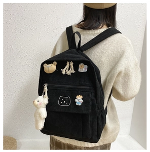 Primer plano de mochila de pana negra con colgante de oso y parches lindos en modelo