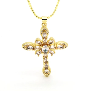 Macro detail of golden floral cross pendant with sparkling zircon gemstones and ball chain