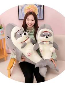 Detailed view of two funny shark-dog hybrid plush pillows held by a person in a living room