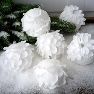 Set of 6 white petal-textured Christmas balls on a snowy pine branch backdrop