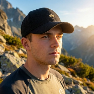 Outdoor herringbone baseball cap with gold embroidery against a snowy mountain background