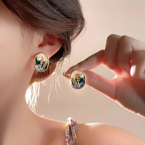 Detailed close-up of oval gold flower earrings with pearls worn by a model