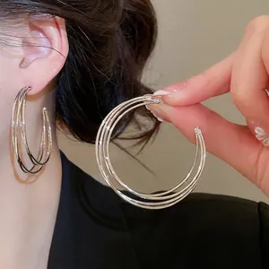 Minimalistische silberne dreilagige C-förmige Creolen am weiblichen Modell