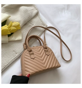 Detail of beige shell bag with V-quilted stitching and adjustable shoulder strap
