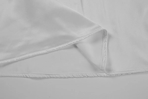 Close-up of white silk dress hem showing neat stitching and elegant satin texture