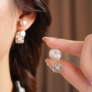 Close-up of double-sided gold flower earrings with white pearls and sparkling zircons