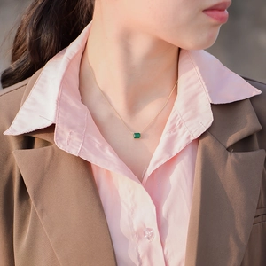 Close-up of a s925 silver gold-plated necklace with a square emerald pendant on a model