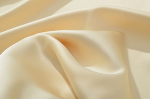 Gros plan détaillé de la texture soyeuse crème avec des reflets et plis élégants