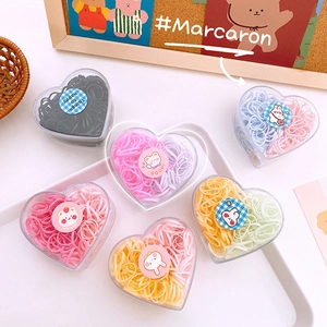 Macro shot of colorful macaron hair elastics in heart-shaped boxes with cute stickers