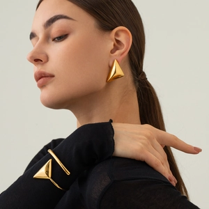 Close-up of a high-polished gold geometric triangle bangle and matching open bracelet
