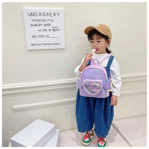 Detailed view of purple glitter backpack with sequin wings on a child model in a studio