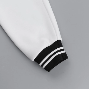 Detail of high-density knit cuffs with white stripes on a black ribbed baseball jacket