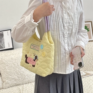 Detalle del bolso acolchado amarillo con bordado de perrito y correas moradas