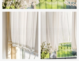 Detail of white mesh lace curtain with vertical stripes and decorative pom-pom fringe edges