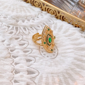 Macro shot of vintage gold marquise ring with green gemstone on white lace background