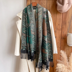 Close-up of bohemian paisley jacquard scarf with black tassels on white winter coat