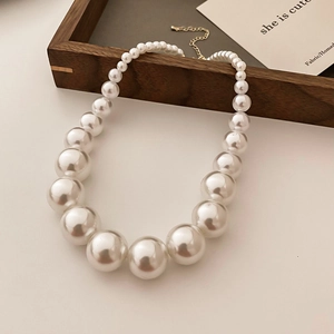 Elegant French vintage gradient pearl necklace with golden clasp on wooden tray