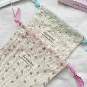 Detailed view of floral corduroy drawstring storage bags with textured fabric and labels