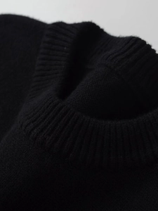 Close-up of ribbed crew neck and soft knitted texture on black long sleeve sweater