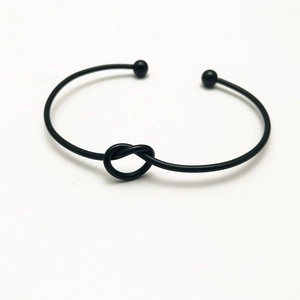 Minimalist black metal knot open cuff bracelet with small ball ends on white background