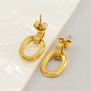 Golden stainless steel oval geometric earrings with triple-ribbed ring on a white tray