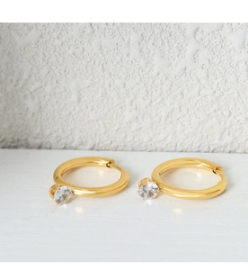 Detailed close-up of gold hoop earrings with sparkling cubic zirconia on a white surface