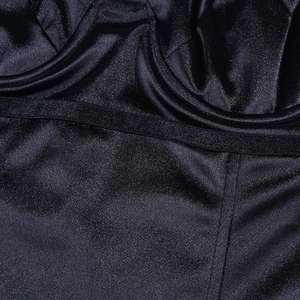 Macro detail of the black satin fabric texture and premium stitching on the bodysuit