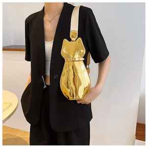 Detailed view of cat-shaped gold metallic bag with beige strap worn by a model