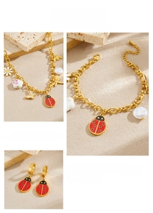 Detail of ladybug and daisy charms on gold stainless steel necklace and earrings